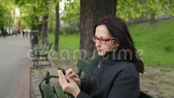 坐在公园长椅上的年轻女子视频的预览图