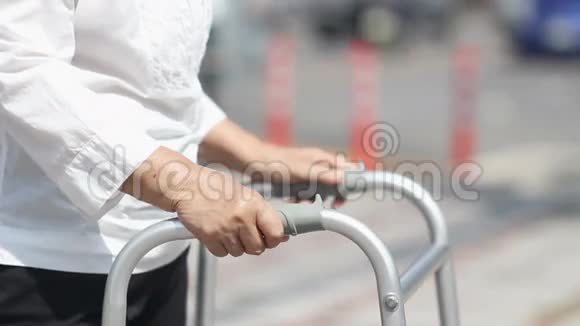 年长的女人用步行器穿过街道视频的预览图