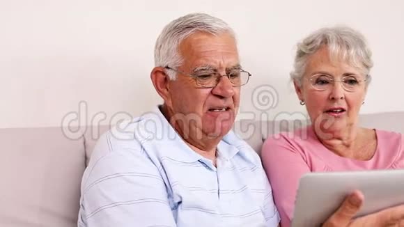 老两口坐在沙发上用平板电脑视频的预览图