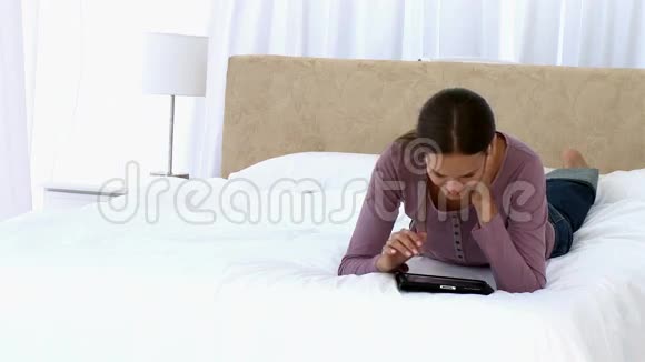一个躺在床上用平板电脑的女孩视频的预览图