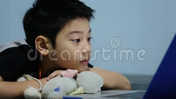 亚洲可爱的男孩在笔记本电脑上看着并微笑视频的预览图