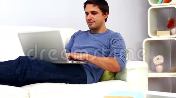 坐在沙发上用笔记本冷静的休闲男人视频的预览图
