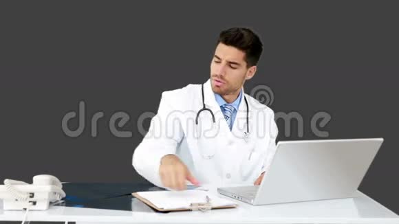 年轻的医生在他的办公桌前工作视频的预览图