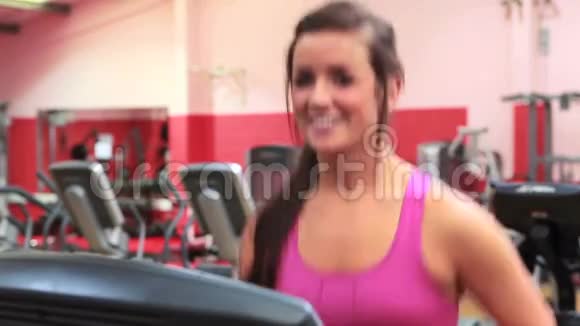 微笑的女人在跑步机上跑步视频的预览图