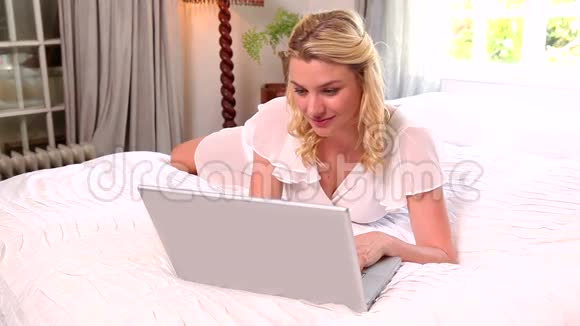 金发躺在床上用笔记本电脑视频的预览图