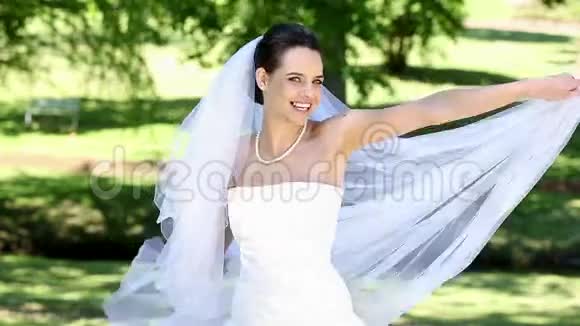 美丽的新娘在公园的镜头前微笑视频的预览图