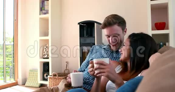 可爱的年轻夫妇在沙发上喝咖啡放松视频的预览图