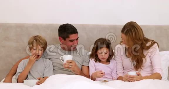 快乐的父母和孩子在床上吃早餐视频的预览图