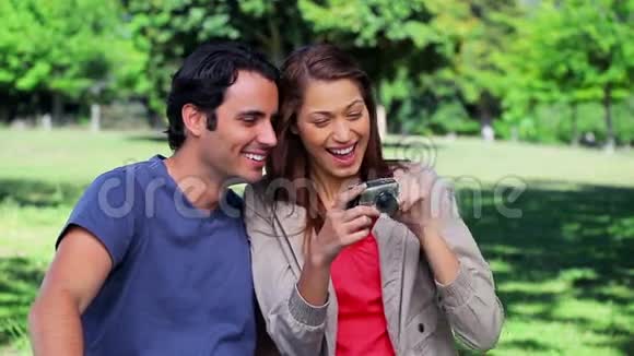 微笑的情侣看着数码相机视频的预览图