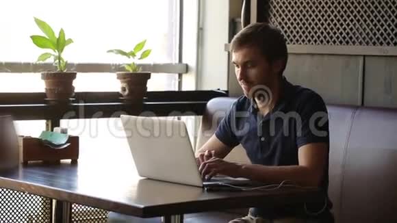 一个坐在咖啡馆里拿着笔记本电脑工作的人视频的预览图