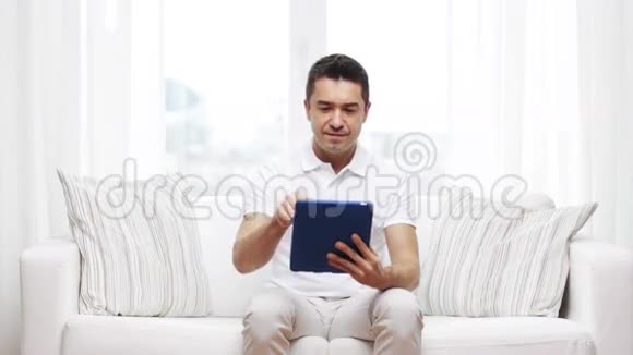 一个在家工作平板电脑的微笑男人视频的预览图