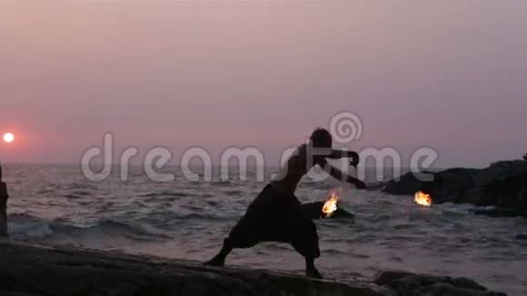 日落时分人类在靠近海洋的悬崖上旋转火坡视频的预览图