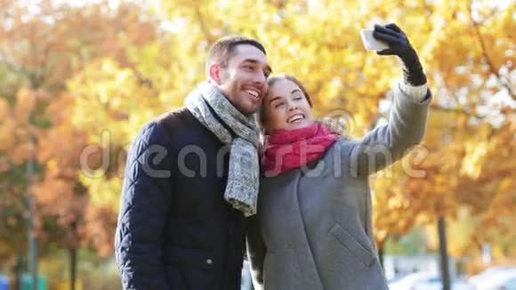 秋日公园有智能手机的微笑情侣视频的预览图