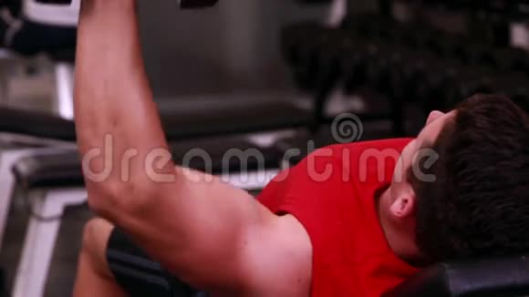 健身男子举起哑铃躺在长凳上视频的预览图