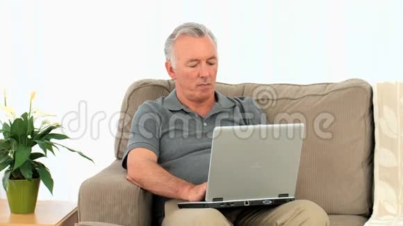 一位在笔记本电脑上工作的老人视频的预览图