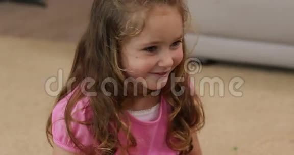 坐在地板上微笑的小女孩视频的预览图