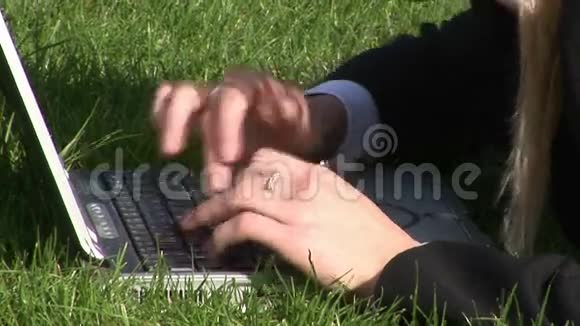 躺在草地上的女人用笔记本电脑视频的预览图