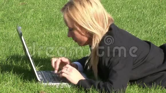 躺在草地上的女人用笔记本电脑视频的预览图