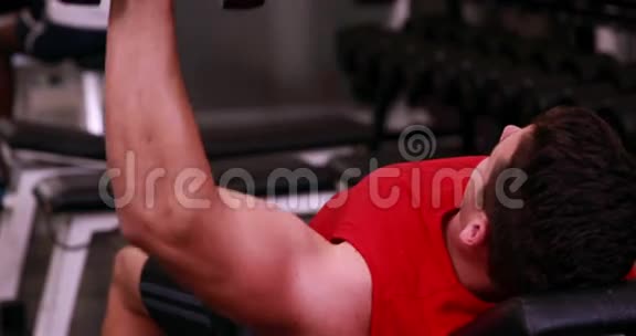 健身男子举起哑铃躺在长凳上视频的预览图