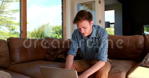 帅哥用笔记本电脑在沙发上放松视频的预览图