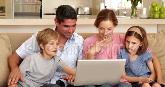使用笔记本电脑坐在沙发上的幸福家庭视频的预览图