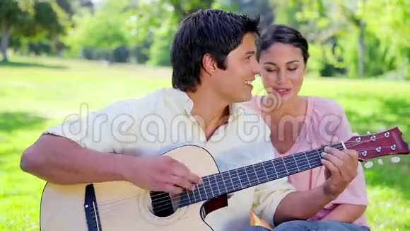 微笑的男人一边弹吉他一边唱歌视频的预览图