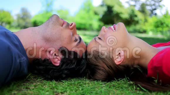 微笑的情侣一起躺在草地上视频的预览图