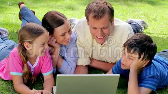微笑的家人躺在一起看着笔记本电脑视频的预览图