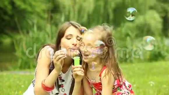 妈妈和小女儿在草地上吹肥皂泡视频的预览图