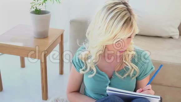 年轻的金发女人在笔记本上写字视频的预览图