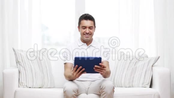 一个在家工作平板电脑的微笑男人视频的预览图