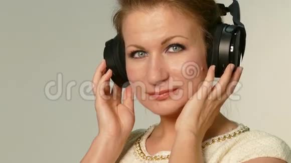 美丽的成年女子听着耳机音乐视频的预览图