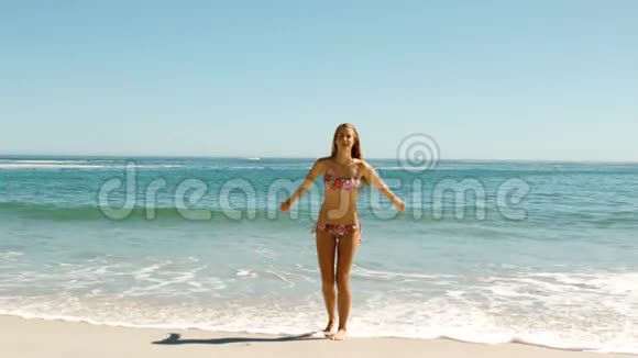 迷人的年轻女子在海滩上跳跃视频的预览图