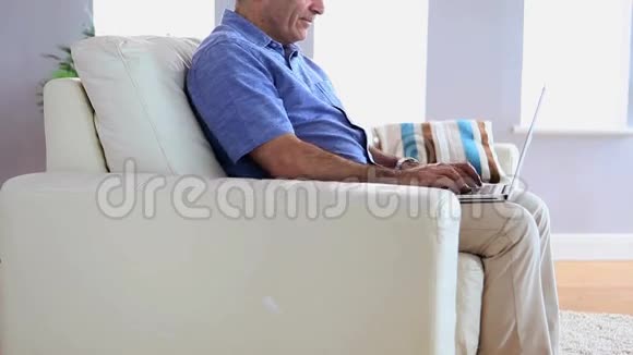 成熟男人在沙发上用笔记本电脑视频的预览图