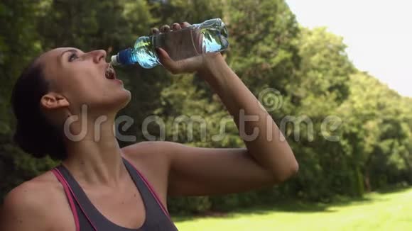 运动型深色头发的女人从水瓶里喝视频的预览图