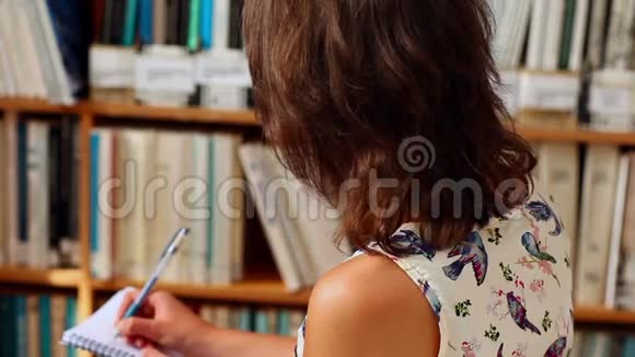 年轻女学生在图书馆写作视频的预览图