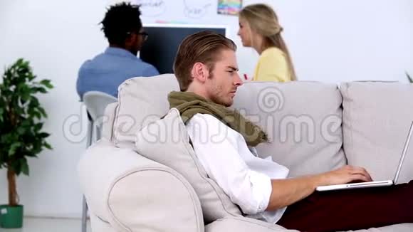 在沙发上用笔记本电脑工作的男人微笑着视频的预览图