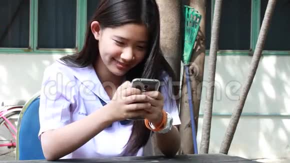 泰国学生十几岁的漂亮女孩用她的手机和微笑视频的预览图