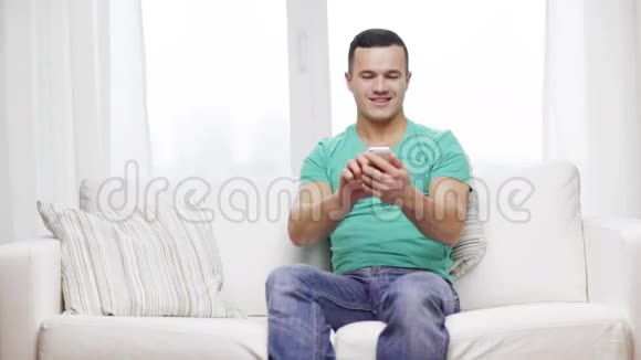 有智能手机的男人坐在家里的沙发上视频的预览图