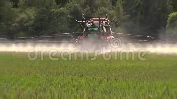 农民用拖拉机喷洒夏季绿色小麦作物农田视频的预览图