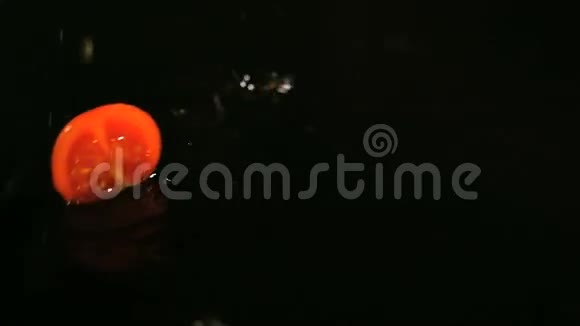 番茄落在黑色表面的水滴缓慢运动视频的预览图