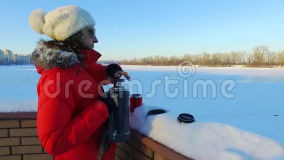 年轻女子在冬季公园里倒茶或咖啡冬季妇女视频的预览图