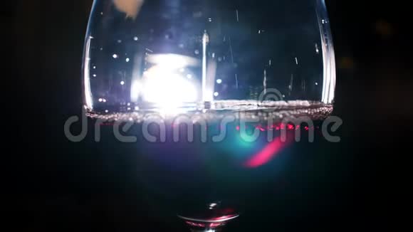 在黑暗中背景上有白光用红色的起泡葡萄酒浇注玻璃库存录像观点视频的预览图