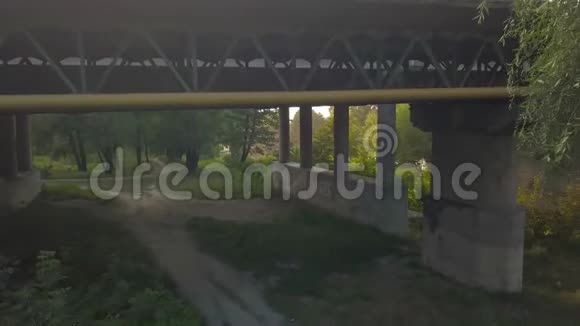 日落时绿树环绕的公路桥的鸟瞰图视频的预览图