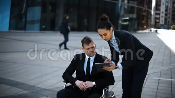 轮椅上的无效老板商人他的女秘书和数字垫一起工作视频的预览图
