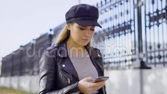 一位年轻而有魅力的女士走在街上在智能手机上打印了一条信息这位女士拿着一部视频的预览图