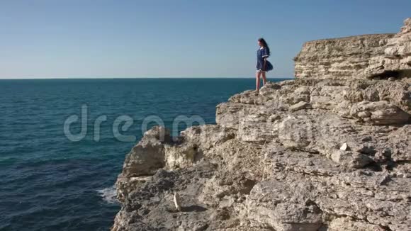 穿着流动裙子的女孩在海边的岩石上视频的预览图