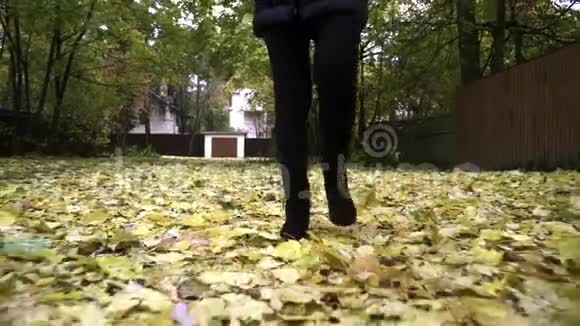 秋日穿着黑色靴子的女人在落叶上行走视频的预览图