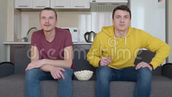 两个男人正在吃爆米花看足球赛视频的预览图