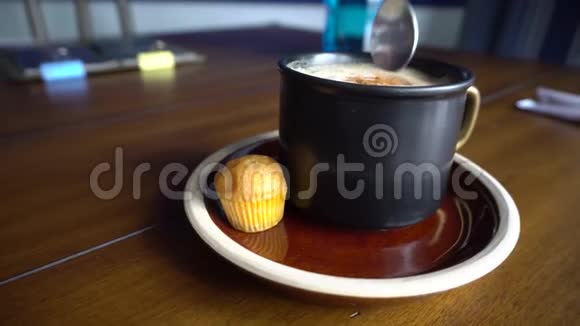 一杯加肉桂皮的咖啡加蛋糕用勺子搅拌糖视频的预览图